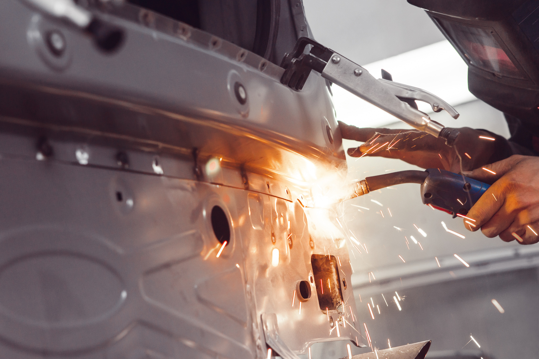 Body shop worker welding car body. Work with carbon dioxide weld.